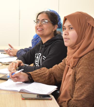 Women learner ESOL. One is wearing a hijab, the other is wearing glasses.